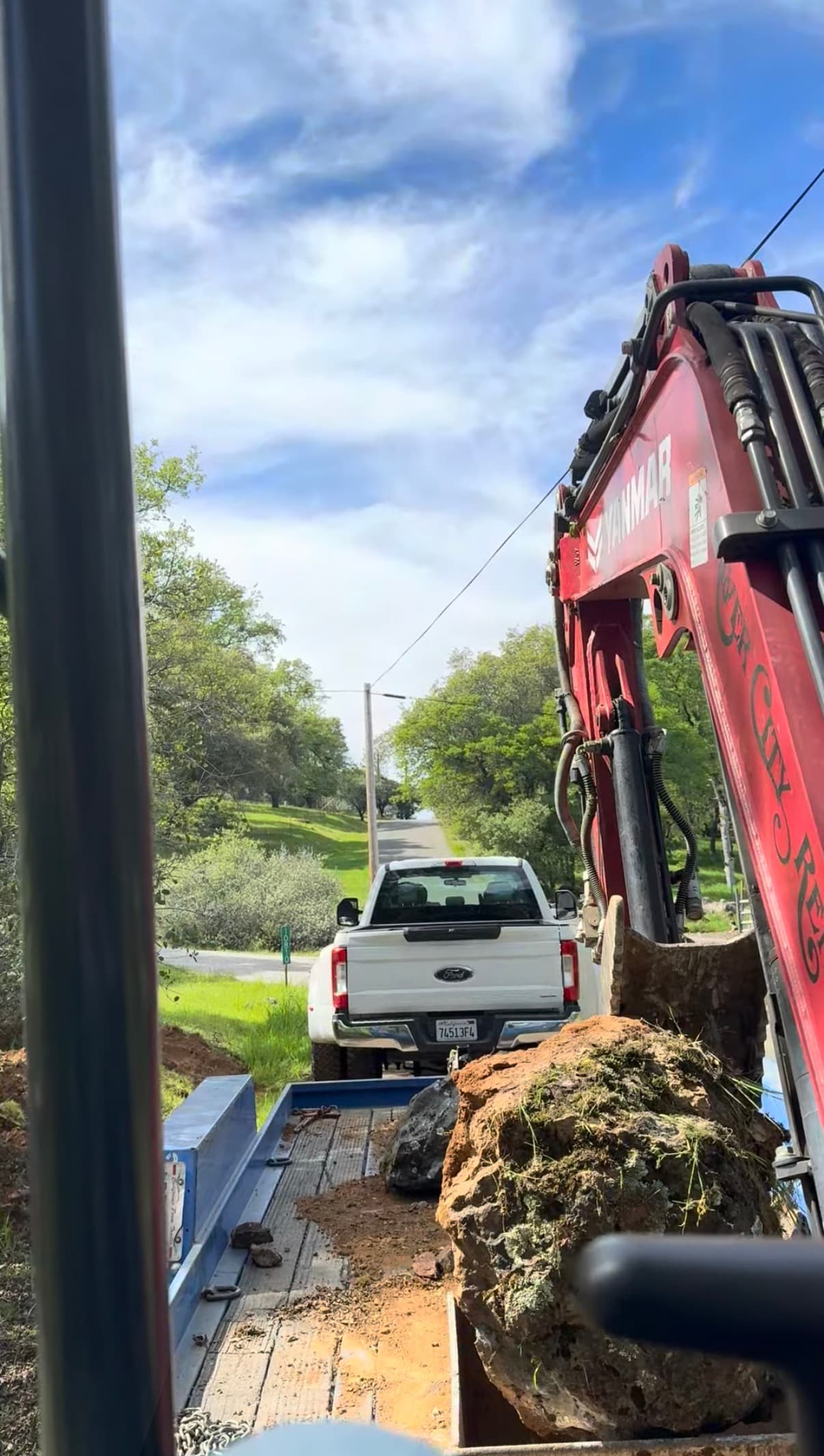 Excavator loading a large native rock for transport