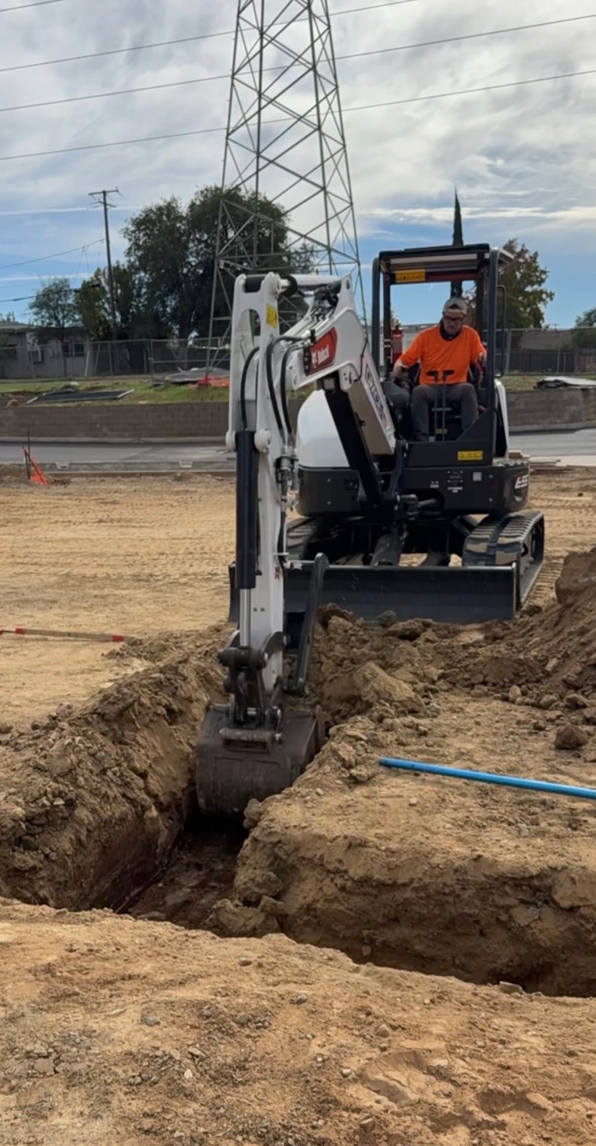 Compact excavator opening a trench on an active site